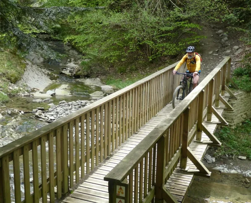 Eric Dutrey, en vtt électrique, sur un pont traversant une cascade au Pays Basque.